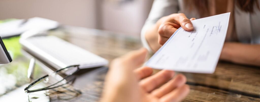 Businesswoman hands a person a cheque.