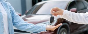 Salesperson handing car keys to new owner of a vehicle.