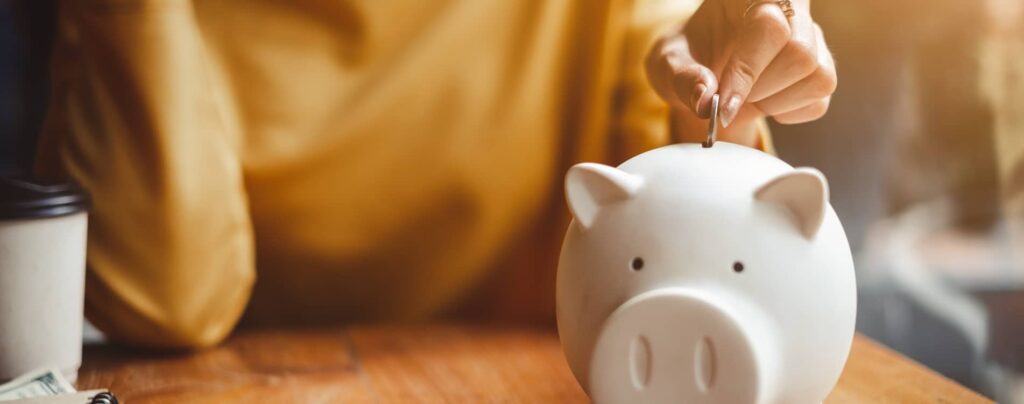 Woman putting a coin into a piggy bank.