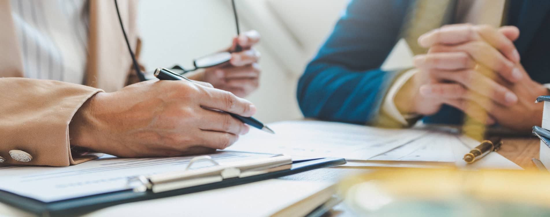 A lawyer speaking to a partner while holding a pen next to paperwork.