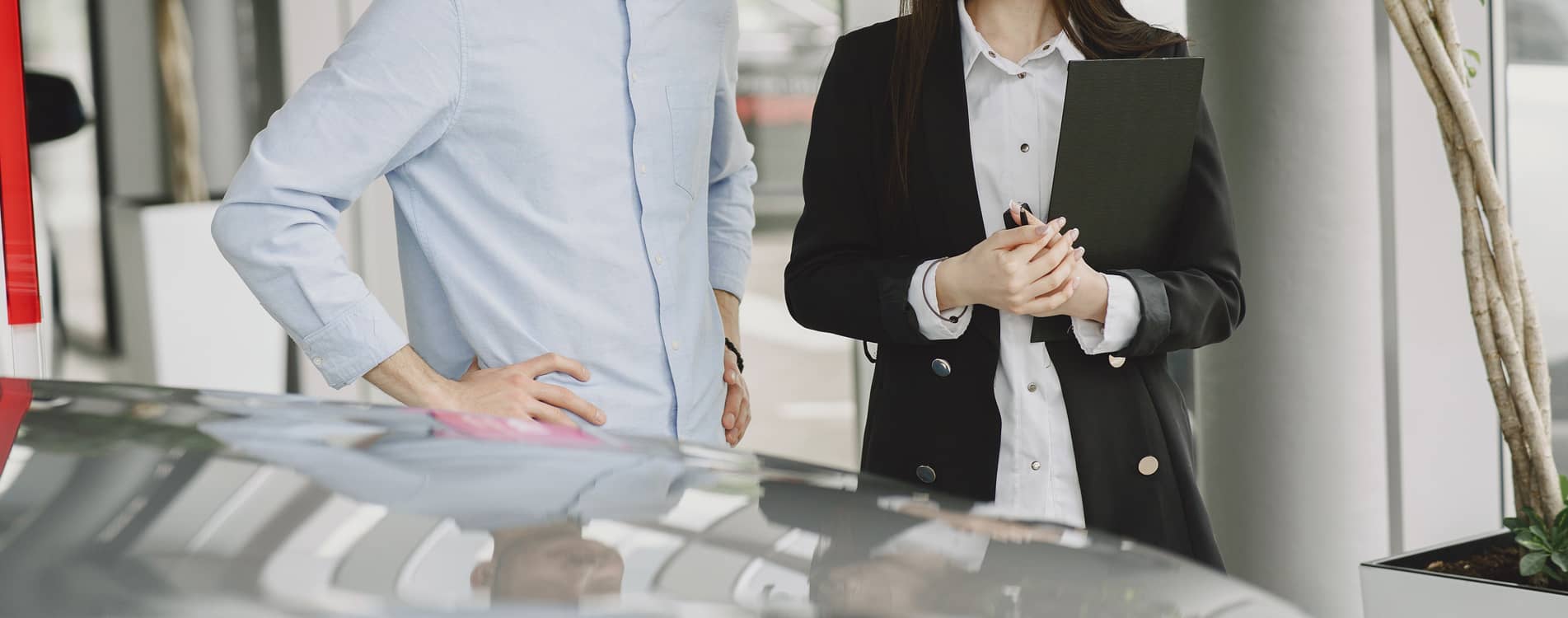 Man and a saleswoman standing next to a car.
